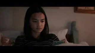 young woman sitting on bed looking at phone — The Social Dilemma