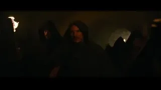 man in hooded cloak with torch in cave — Gladiator 2
