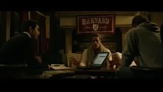 Three men looking at laptop with Harvard banner — The Social Network