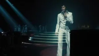 man in white suit on stage with microphone — Blade Runner 2049