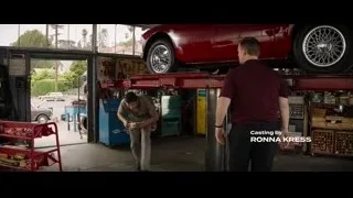 two men working on red car in garage — Ford v Ferrari