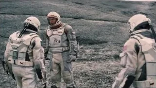 astronauts with gun on rocky barren surface — Interstellar