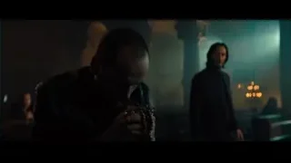 man praying in dimly lit room with candles — John Wick: Chapter 4